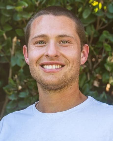 Wyatt Fleming smiling outdoors in front of a green hedge