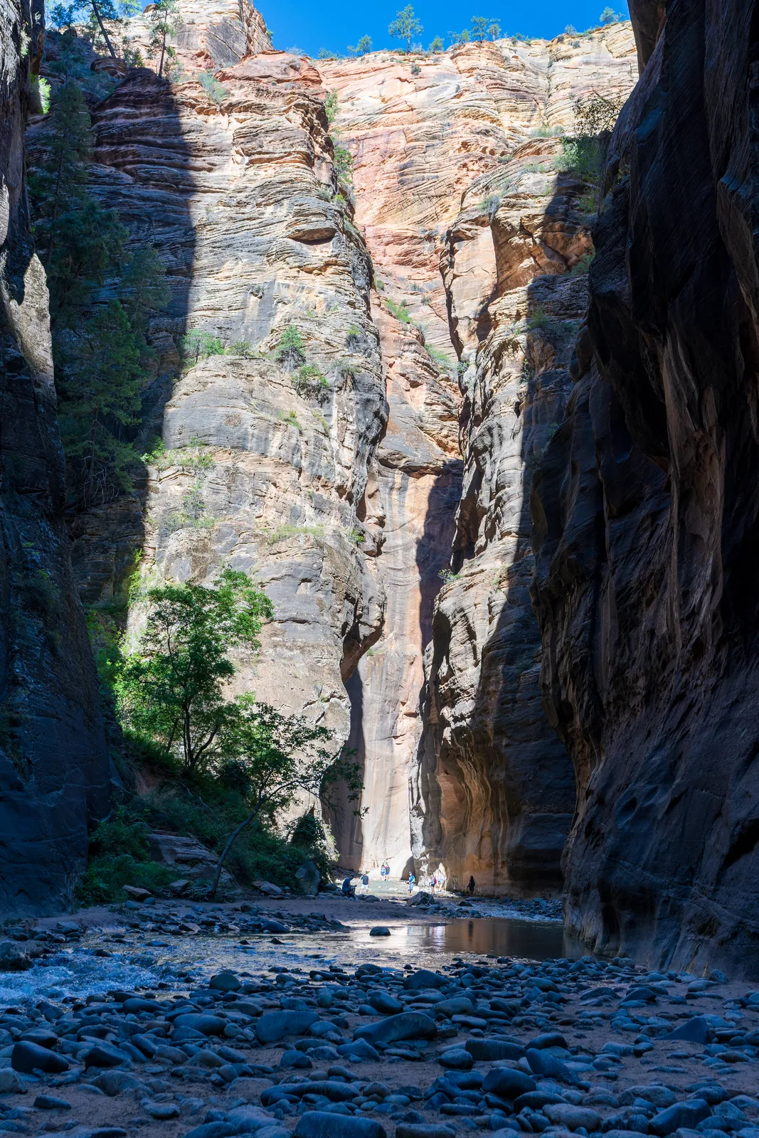 Dark framing walls open onto a sunlit fluted cliff mirrored in a still pool